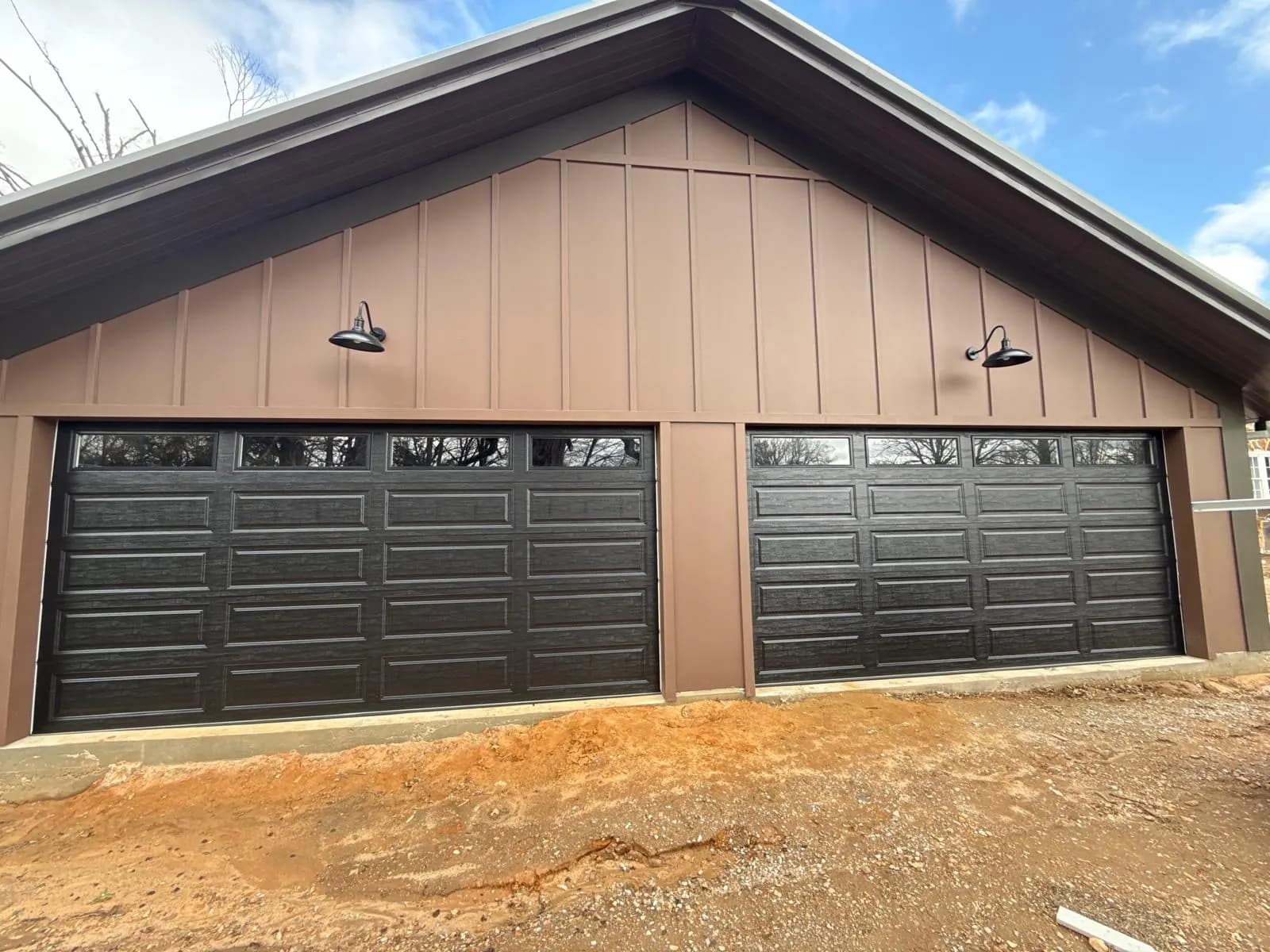 Two black raised-panel garage doors with rectangular top windows