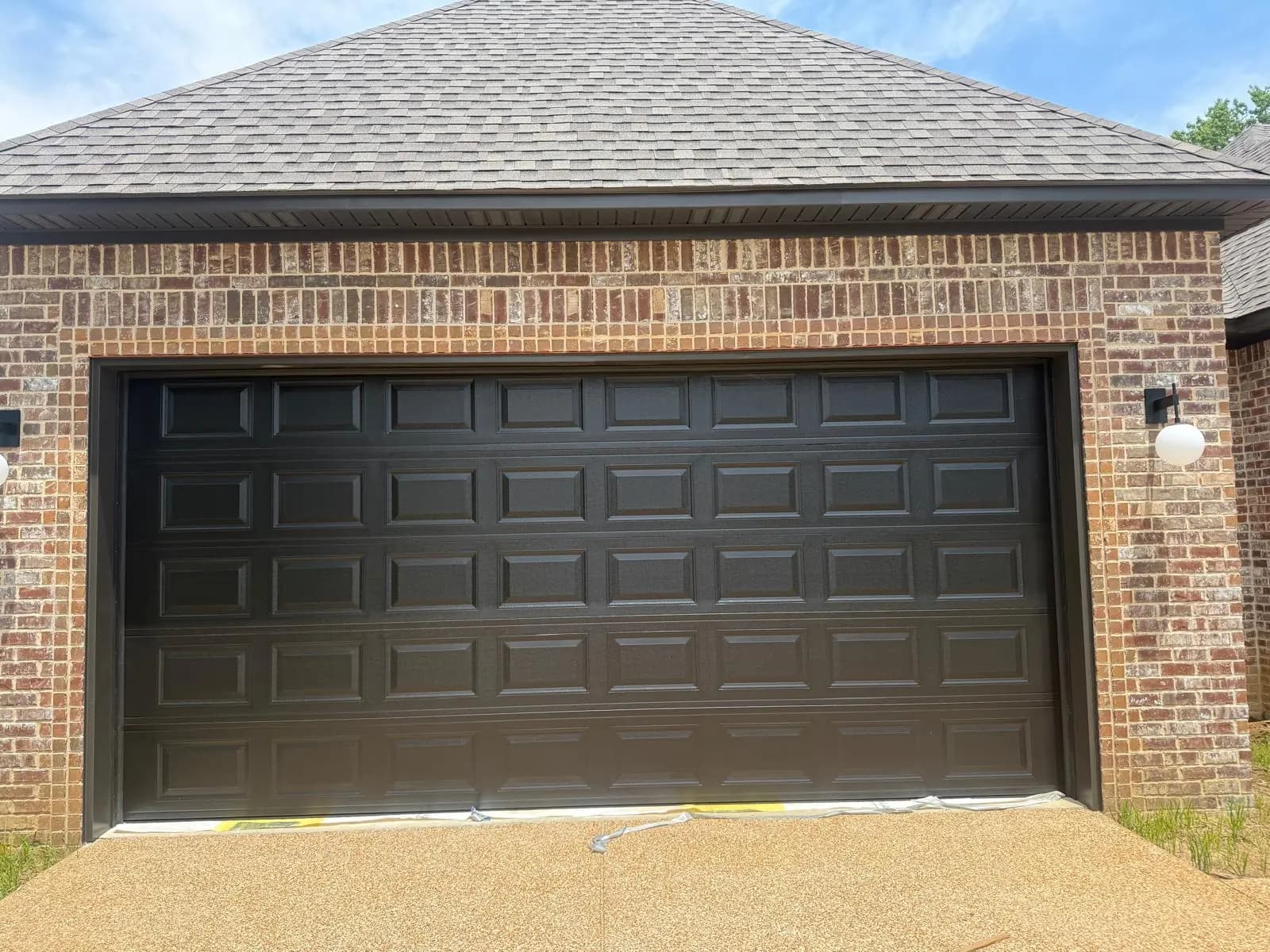 Black double-width garage door with raised rectangular panels